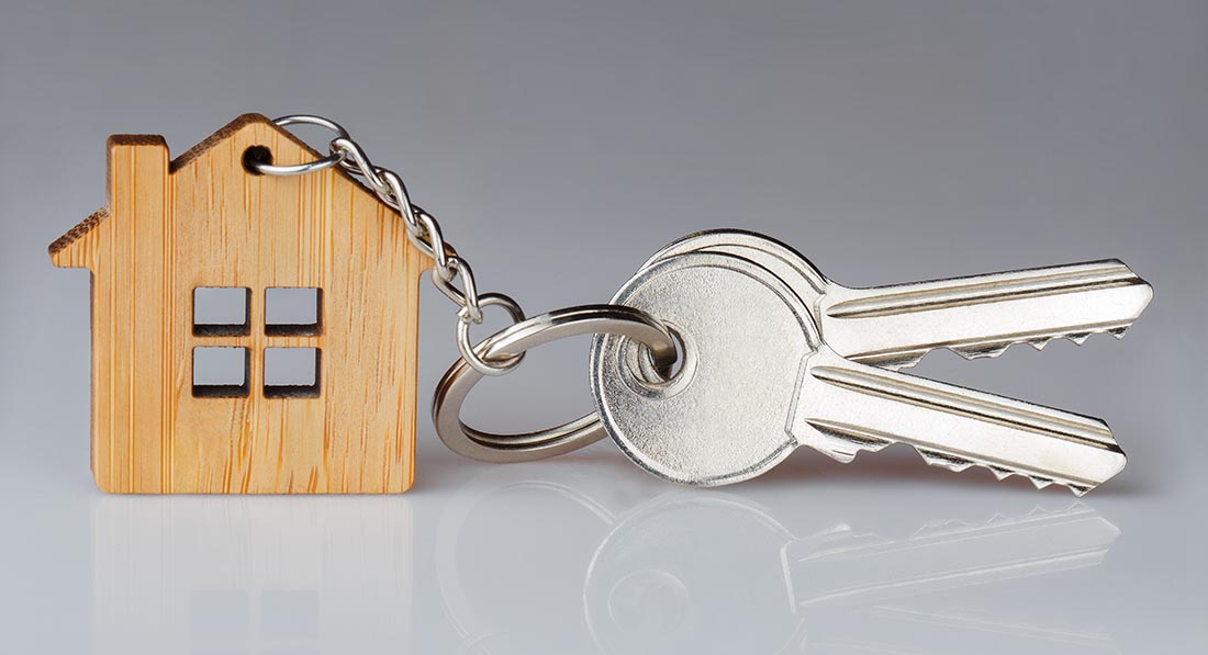 House keys with a house shaped keychain on gray background